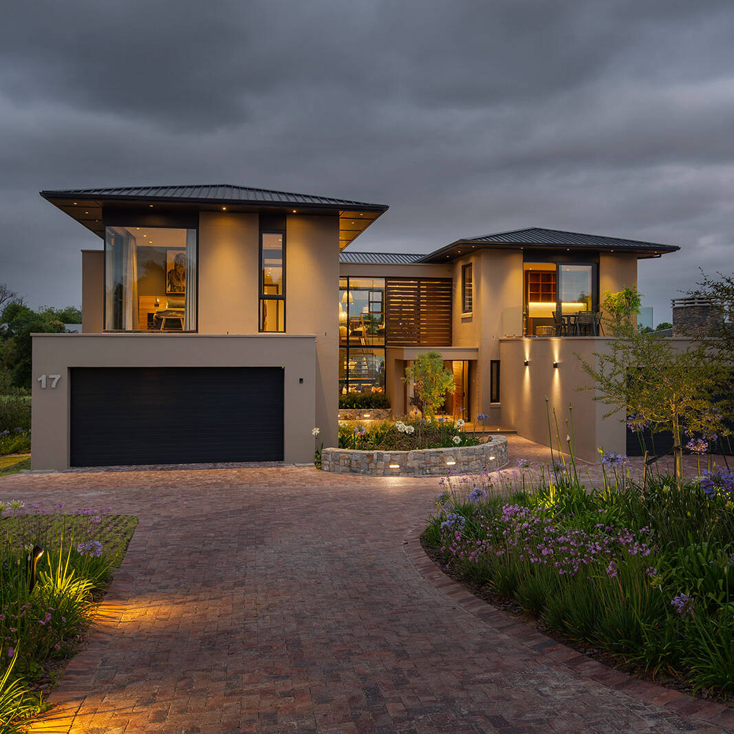 Front elevation at dusk with landscaped driveway and warm interior lighting showcasing contemporary fancourt architecture