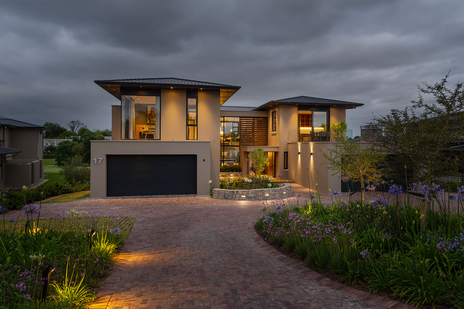 Front elevation at dusk with landscaped driveway and warm interior lighting showcasing contemporary fancourt architecture