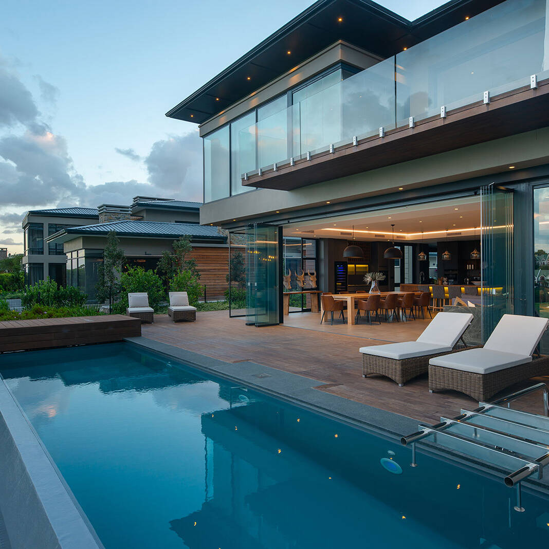 Pool terrace with glass balustrade and sliding doors opening to the main living spaces