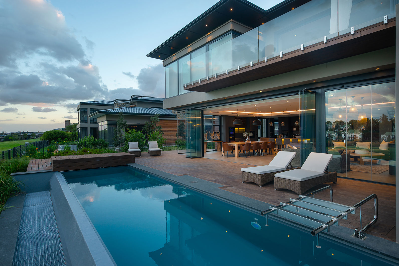 Pool terrace with glass balustrade and sliding doors opening to the main living spaces