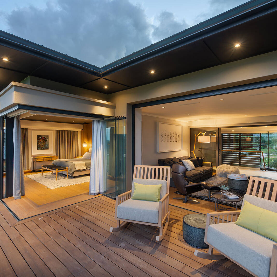 Upper deck with bedroom and lounge connected to outdoor seating under extended eaves