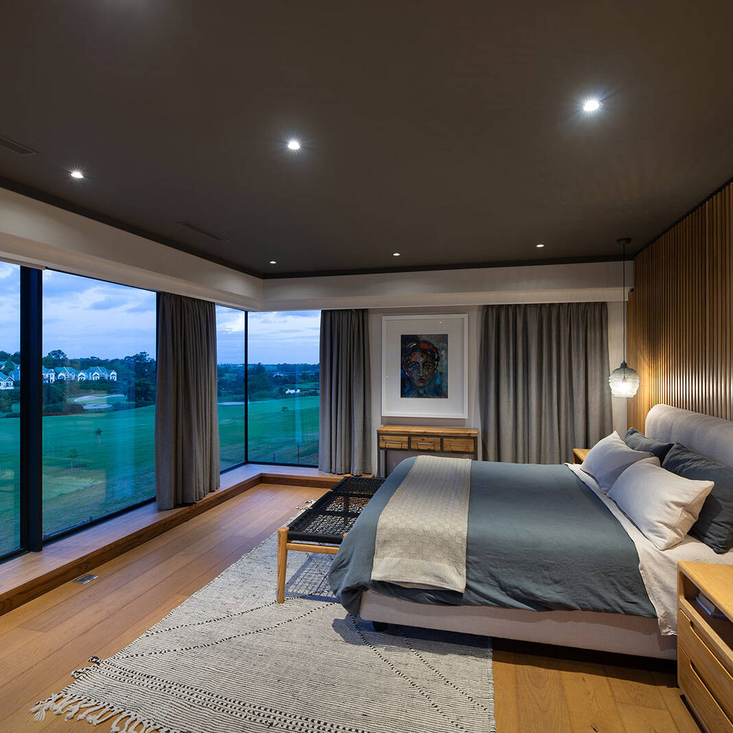 Corner main bedroom with full height glazing overlooking the golf course