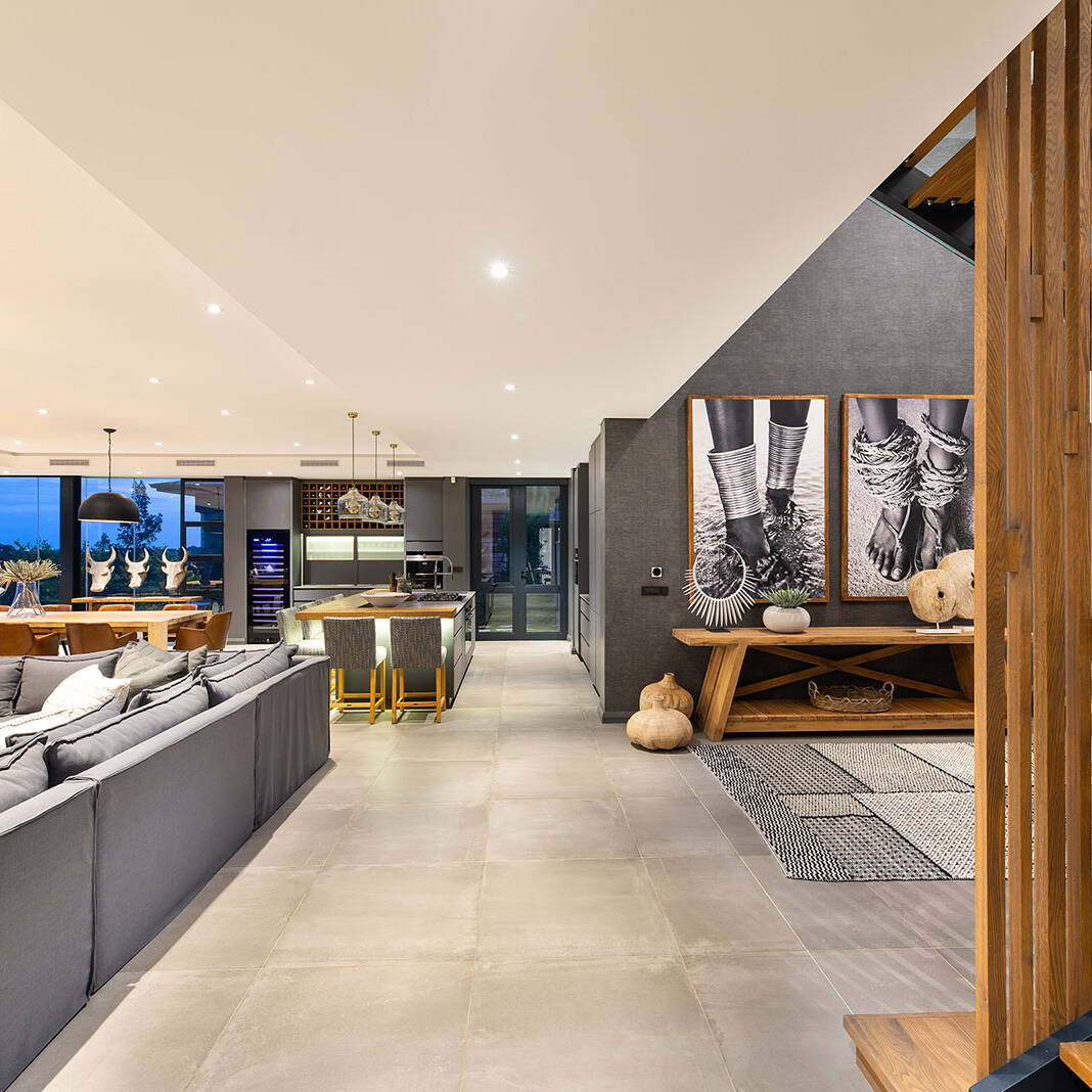 Ground floor living and dining space arranged around a long table and large openings to the terrace