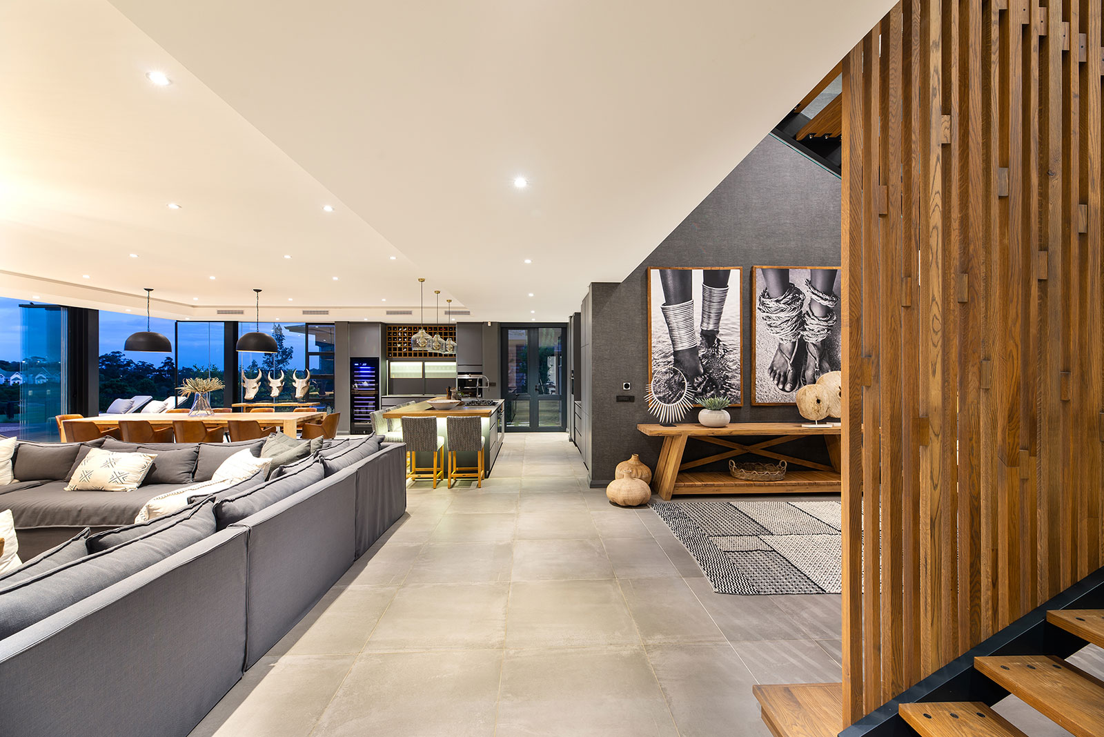 Ground floor living and dining space arranged around a long table and large openings to the terrace