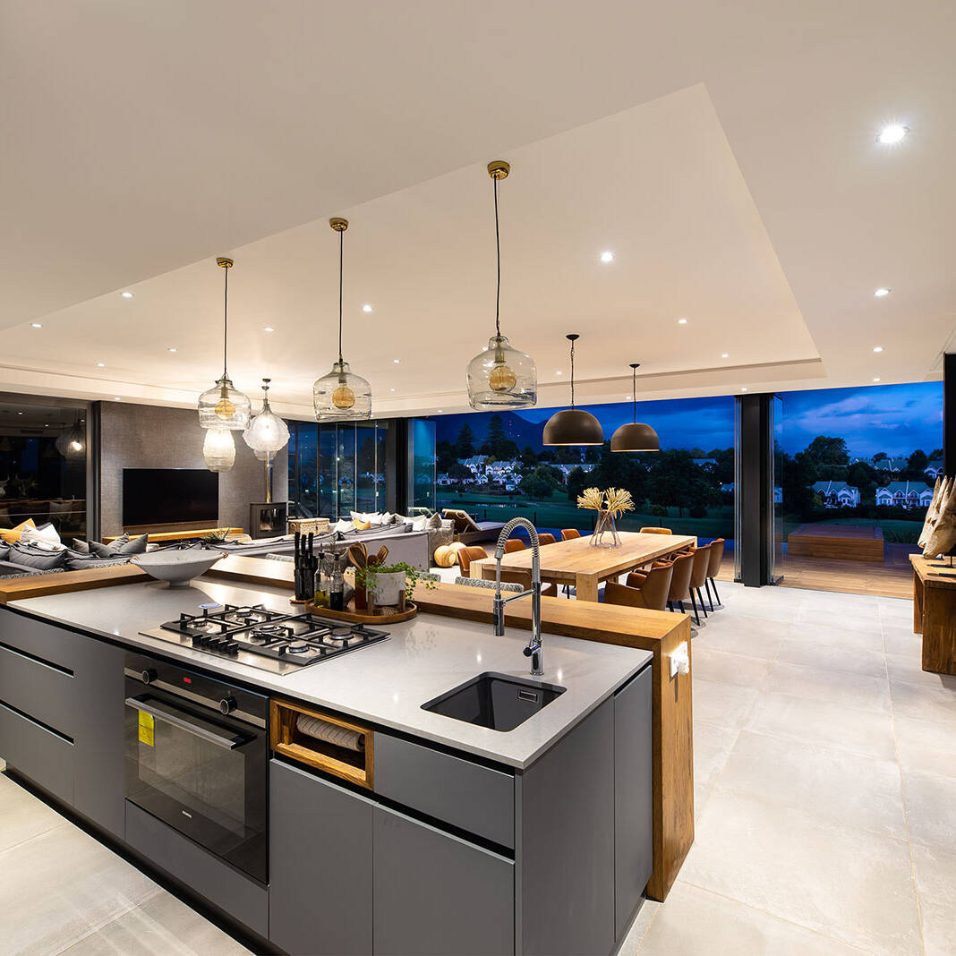 Kitchen island with integrated hob and breakfast counter facing the open plan living area