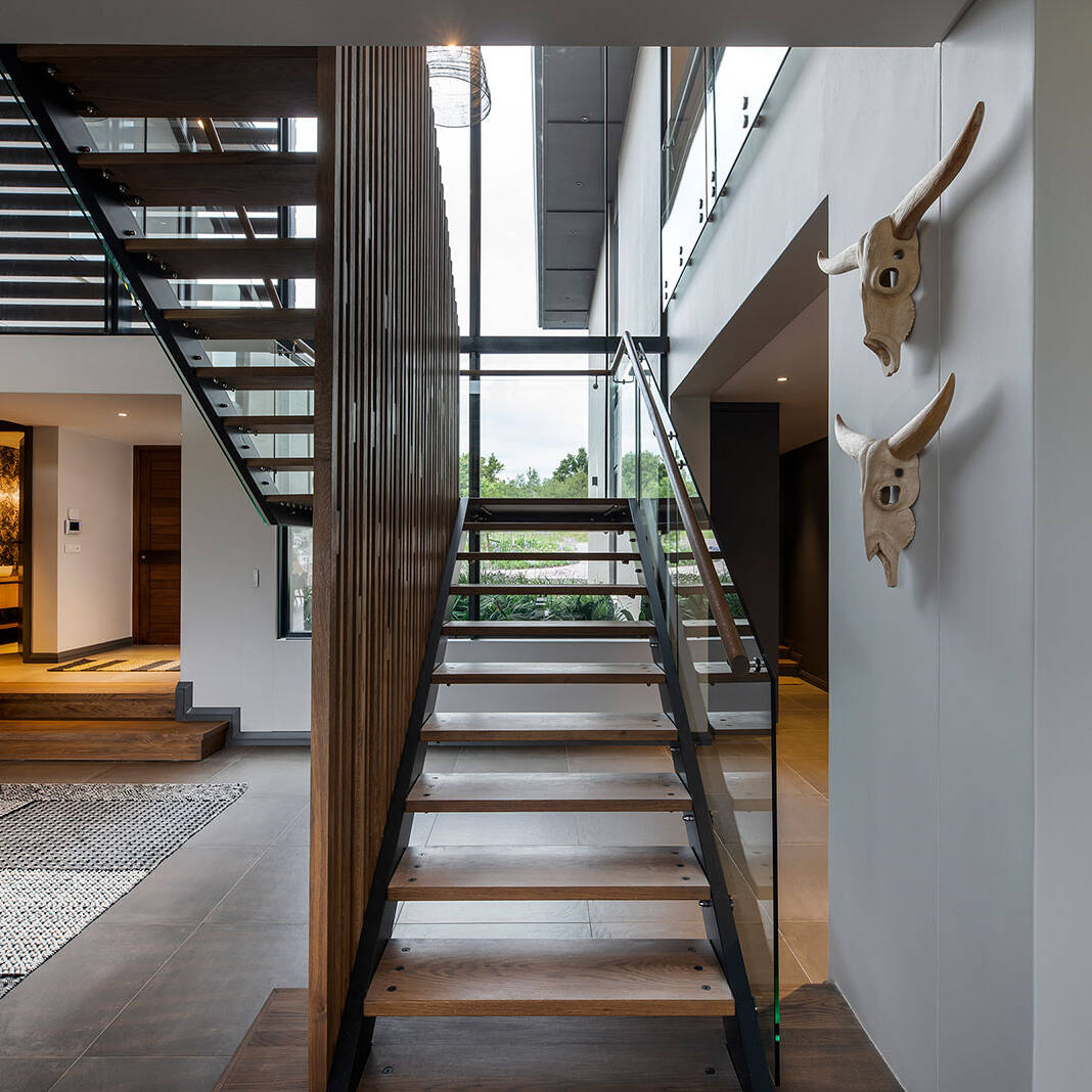 Double volume entry hall with central timber and glass staircase exemplifying contemporary fancourt architecture