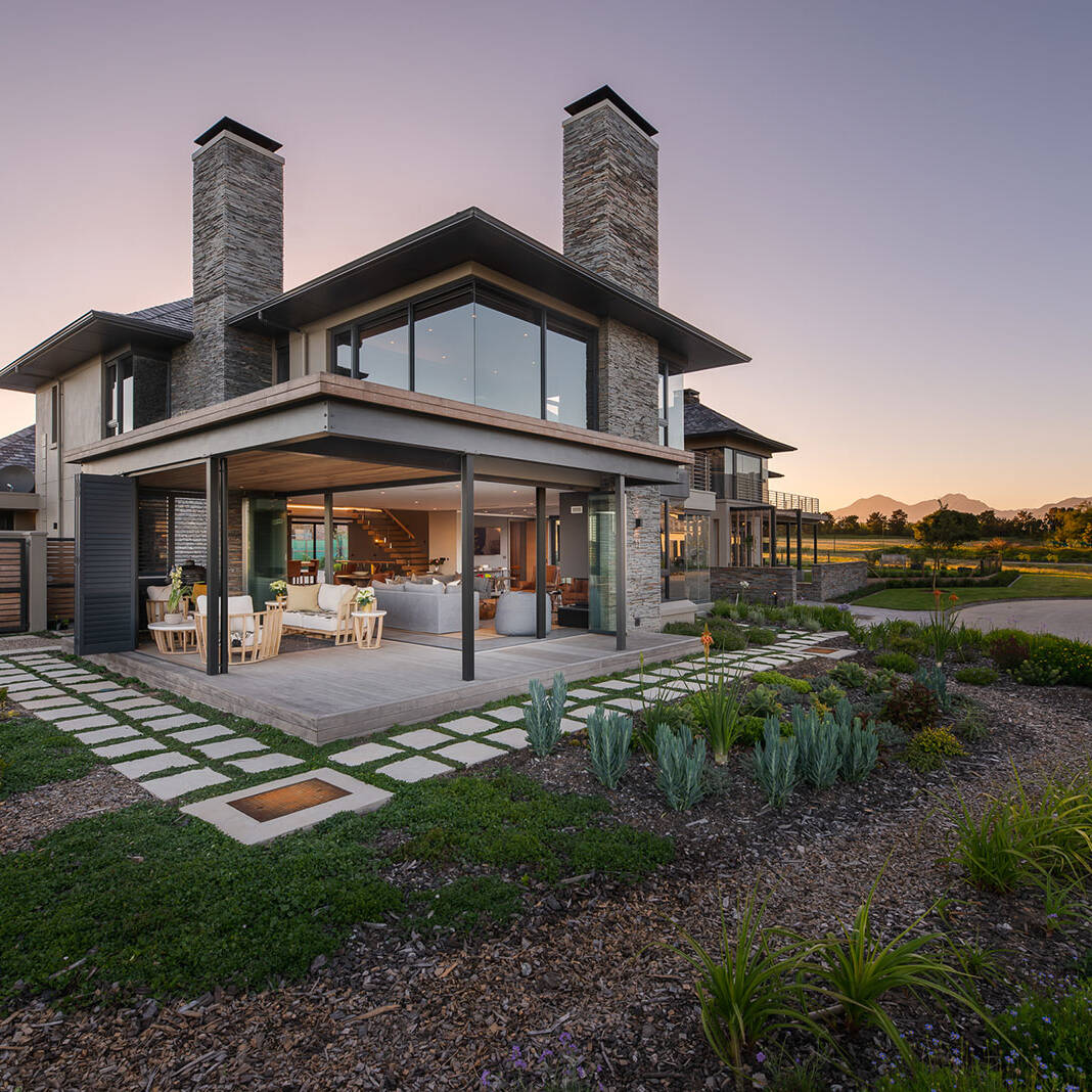 Evening exterior with stone cladding and folding doors to terrace
