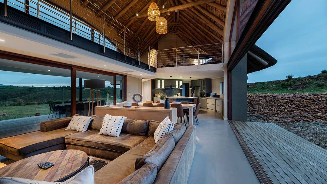 Living pavilion at dusk with thatched ceiling and sliding doors to both sides