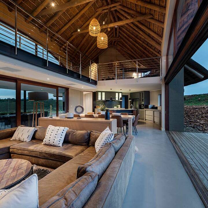 Living pavilion at dusk with thatched ceiling and sliding doors to both sides