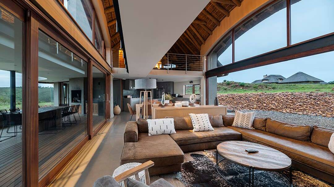 Double-volume living area opening to deck and views, seen from lounge toward kitchen, bushveld architecture