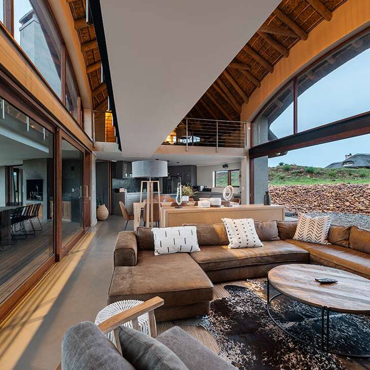 Double-volume living area opening to deck and views, seen from lounge toward kitchen, bushveld architecture