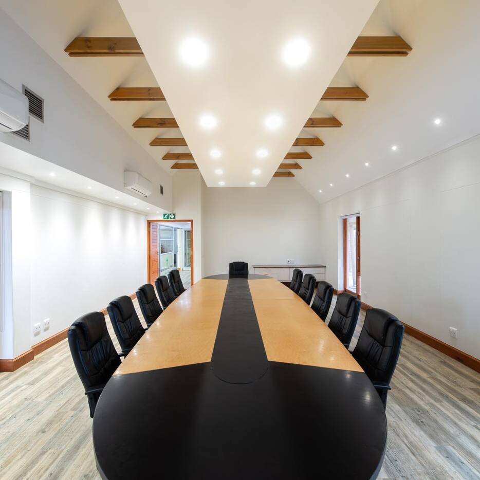 Central view of boardroom under illuminated raft ceiling with timber doors.