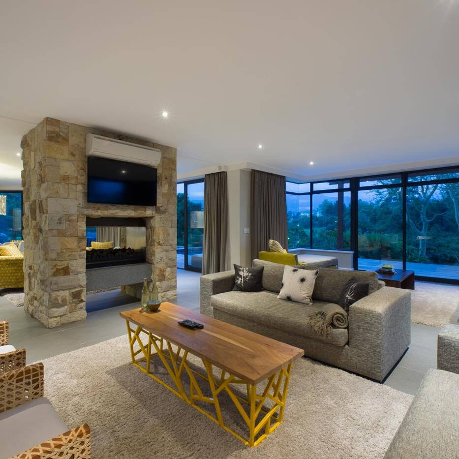 Living area with stone fireplace dividing lounge and dining spaces