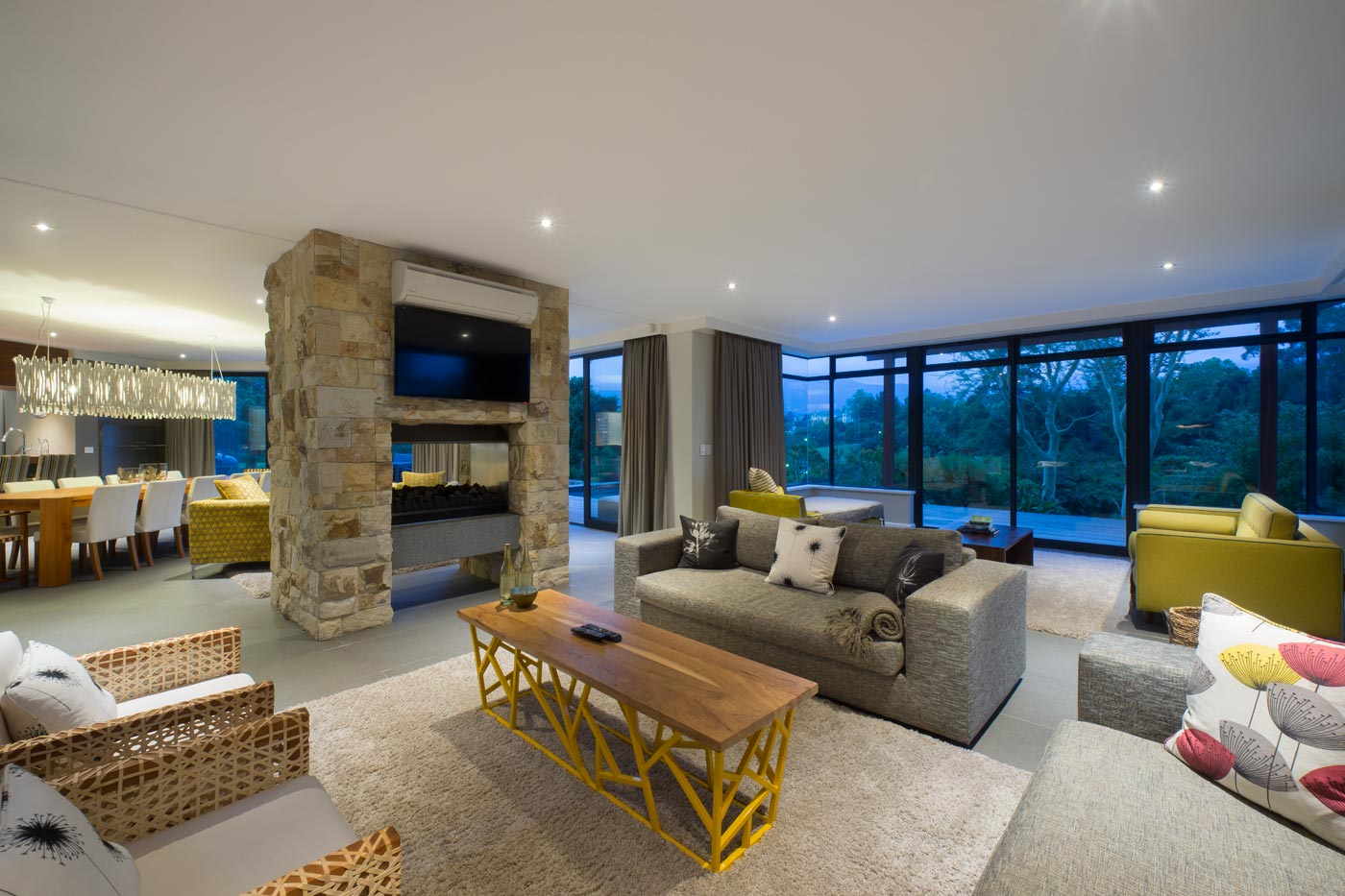 Living area with stone fireplace dividing lounge and dining spaces
