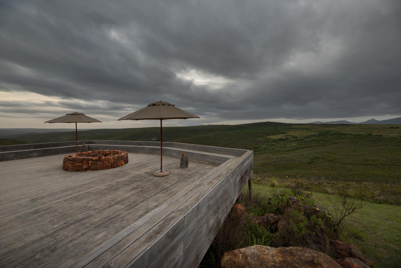 Elevated timber deck with fire pit and umbrellas overlooking fynbos in the Garden Route.