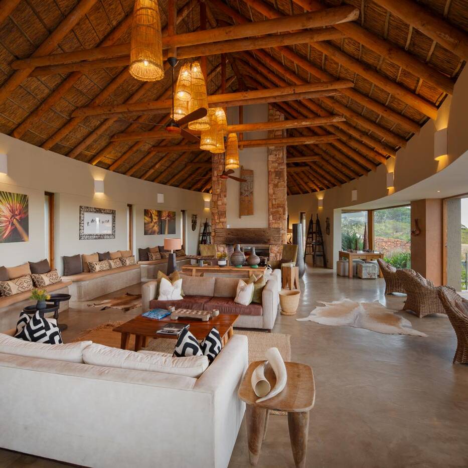 Central stone fireplace beneath a thatched ceiling in the lodge living room, South Africa