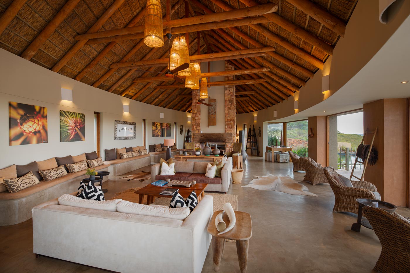 Central stone fireplace beneath a thatched ceiling in the lodge living room, South Africa