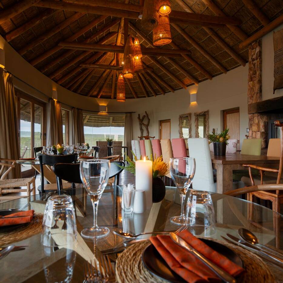 Long thatched lounge with built in seating and panoramic glazing facing the valley