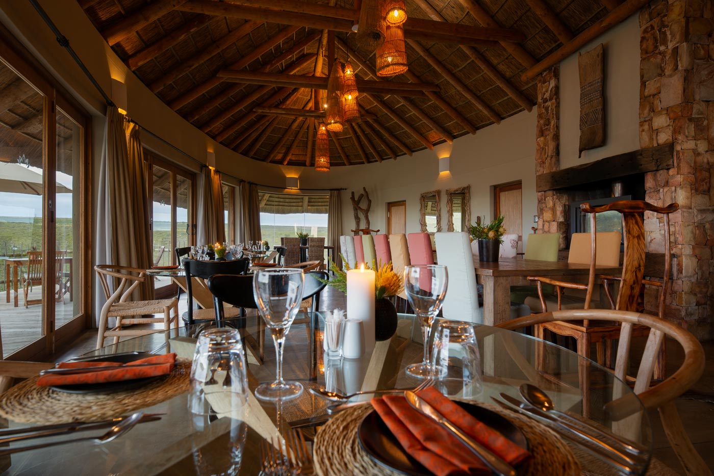 Long thatched lounge with built in seating and panoramic glazing facing the valley