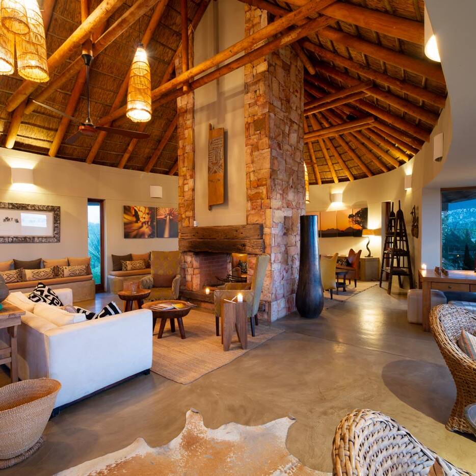 Curved lodge lounge under a thatched roof with woven seating in South Africa