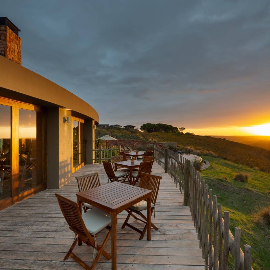 Dining room with glass doors seen from the deck and views across the reserve, modern Garden Route lodge architecture.