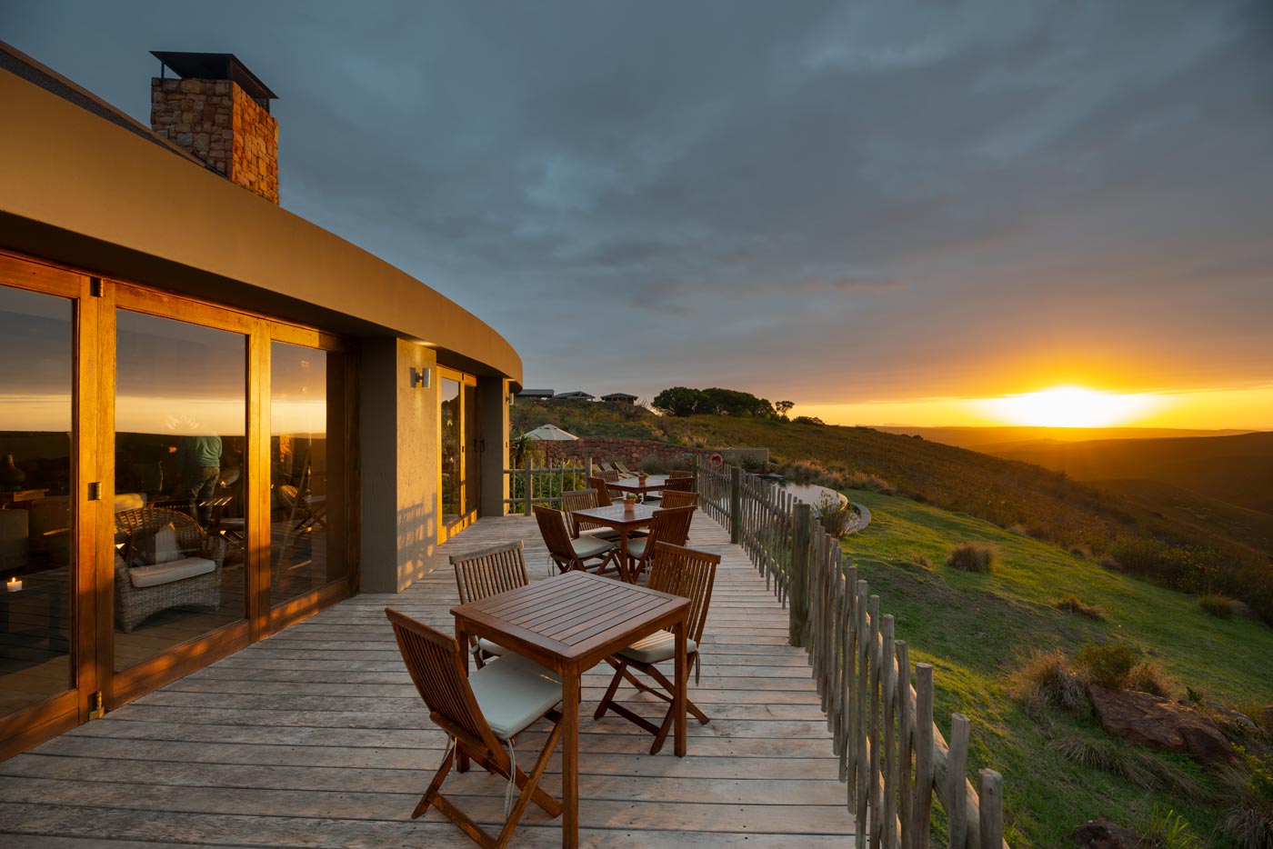 Dining room with glass doors seen from the deck and views across the reserve, modern Garden Route lodge architecture.