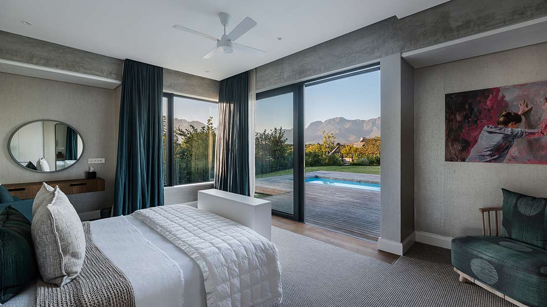 Main bedroom opening to timber deck and pool with Outeniqua mountain views, House 3002