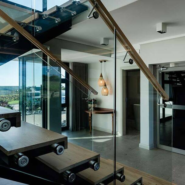 Floating timber staircase with glass balustrade — precision detailing in golf estate architecture
