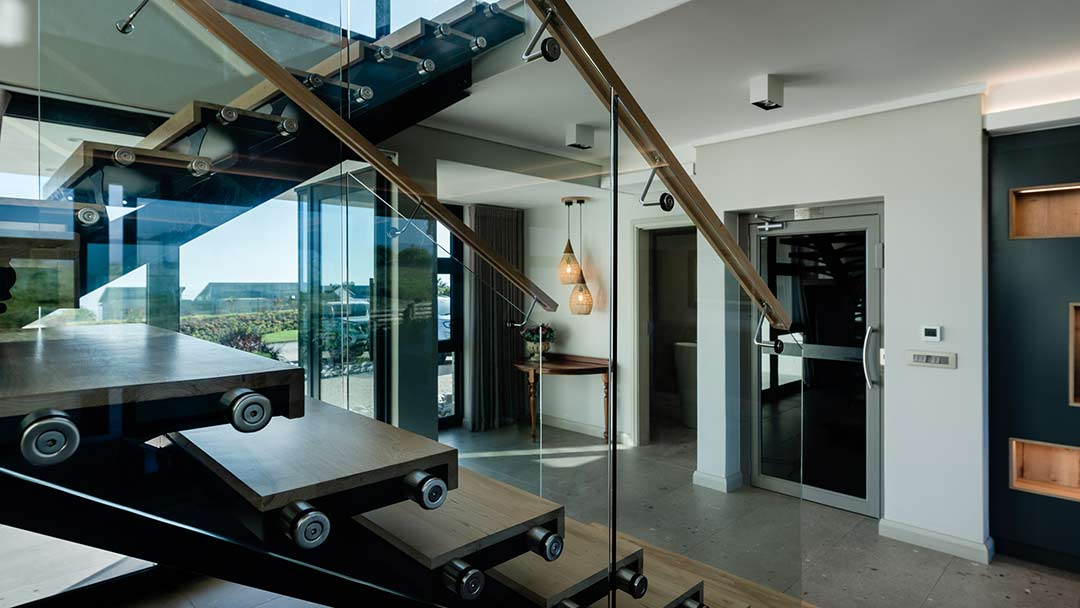 Floating timber staircase with glass balustrade — precision detailing in golf estate architecture