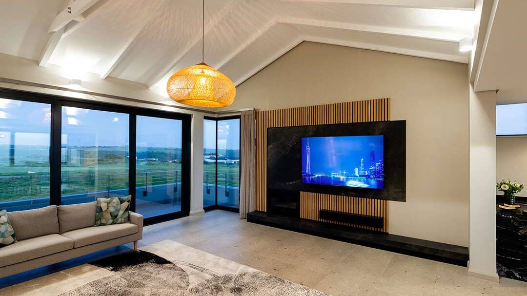 Living room with bespoke TV wall and fairway views — golf estate architecture