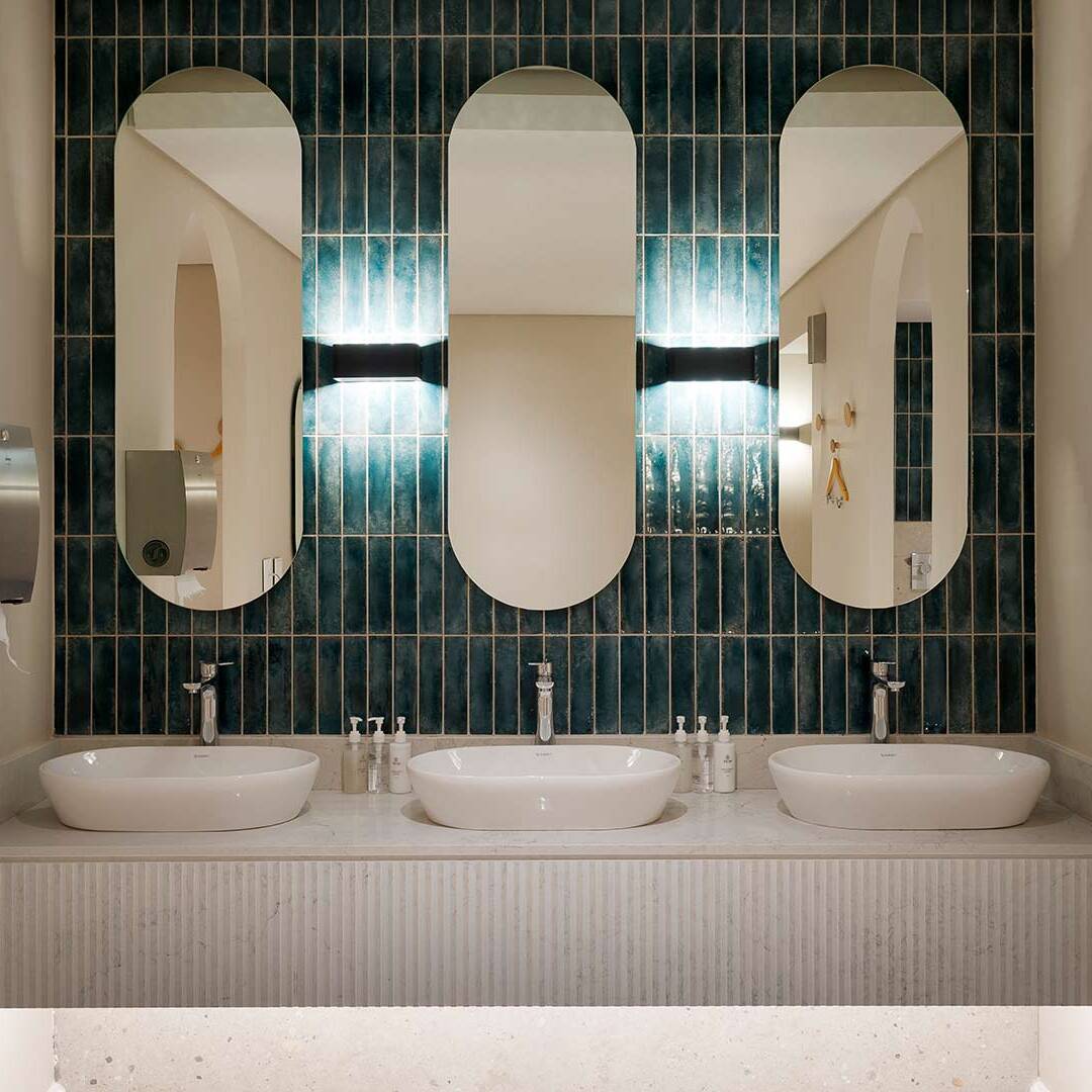 Triple-basin vanity detail with fluted counter and teal tiles — resort interior design