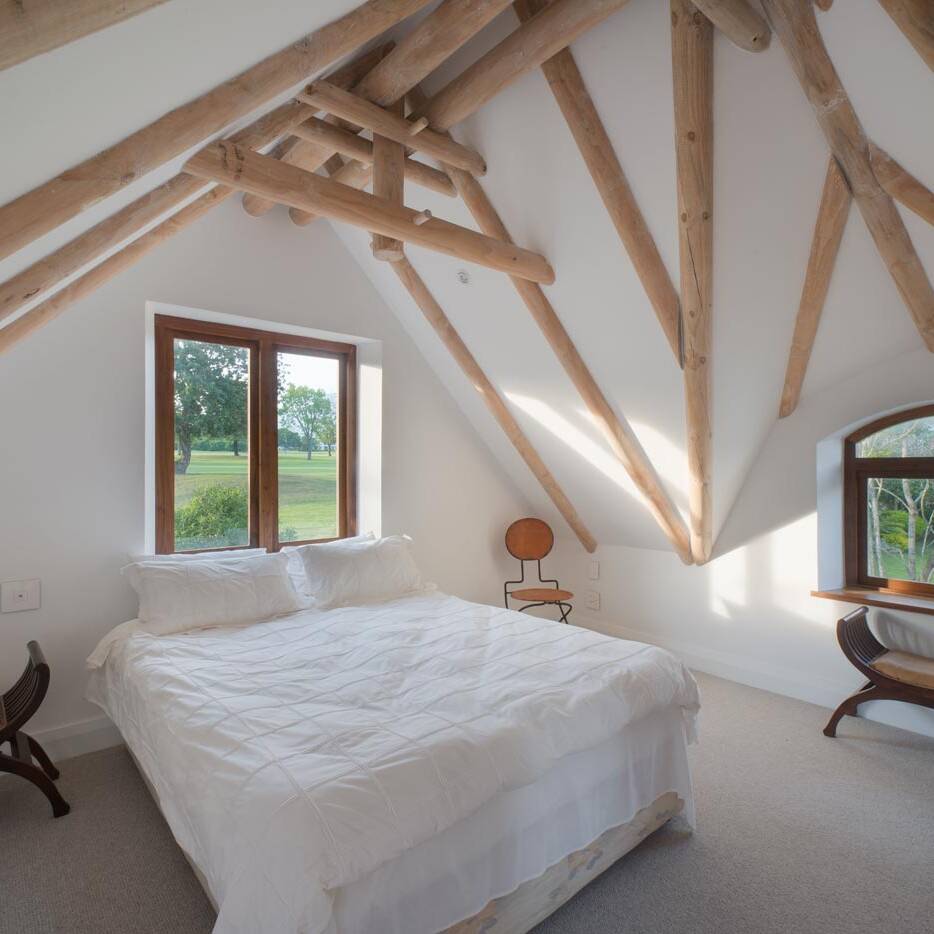 Bedroom with exposed roof beams in Fancourt, South Africa.