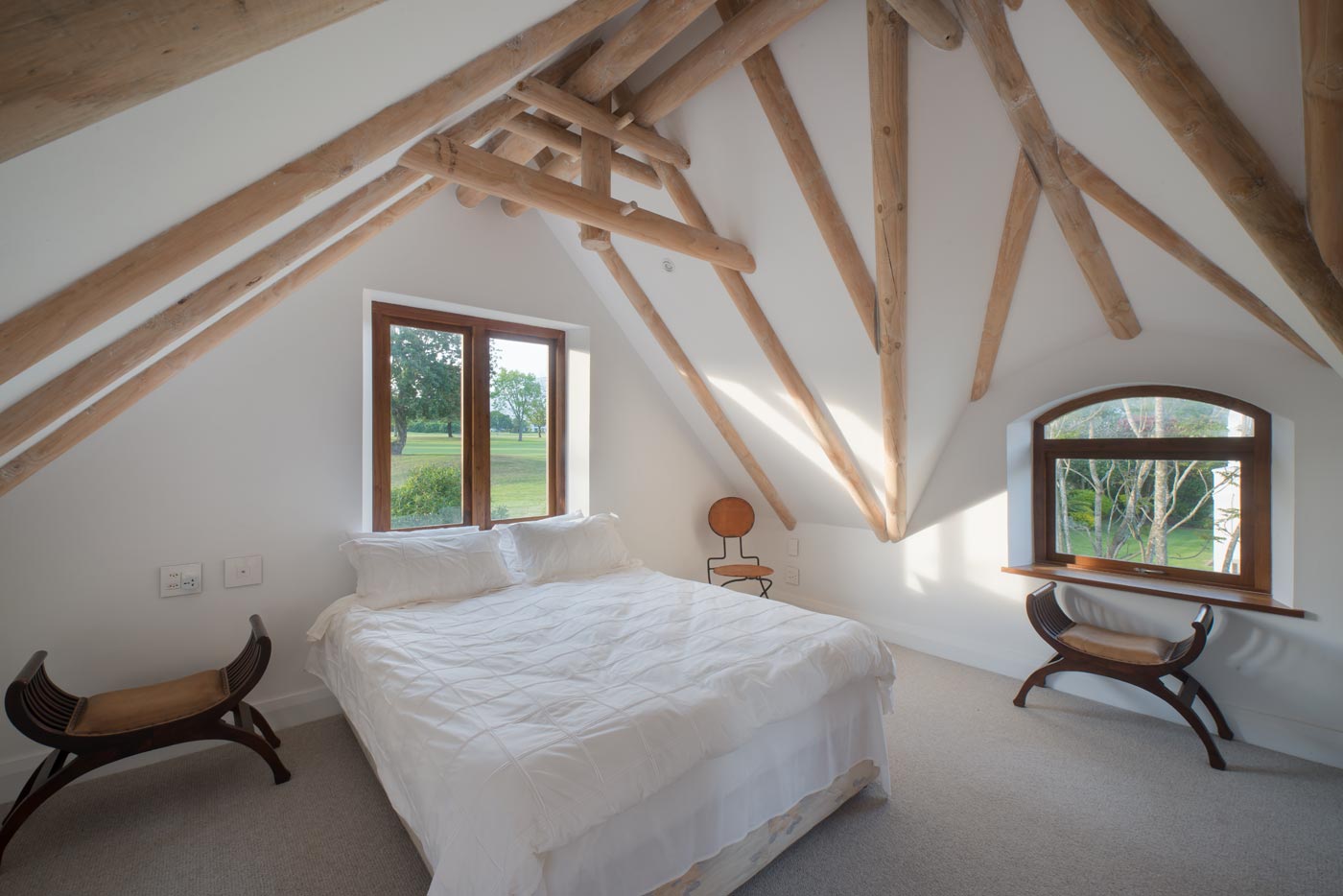 Bedroom with exposed roof beams in Fancourt, South Africa.