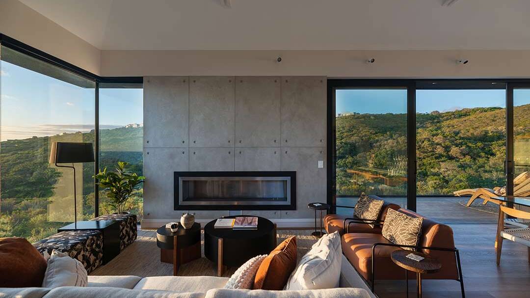Living room with concrete fireplace wall and corner glazing to coastal fynbos, House 1418