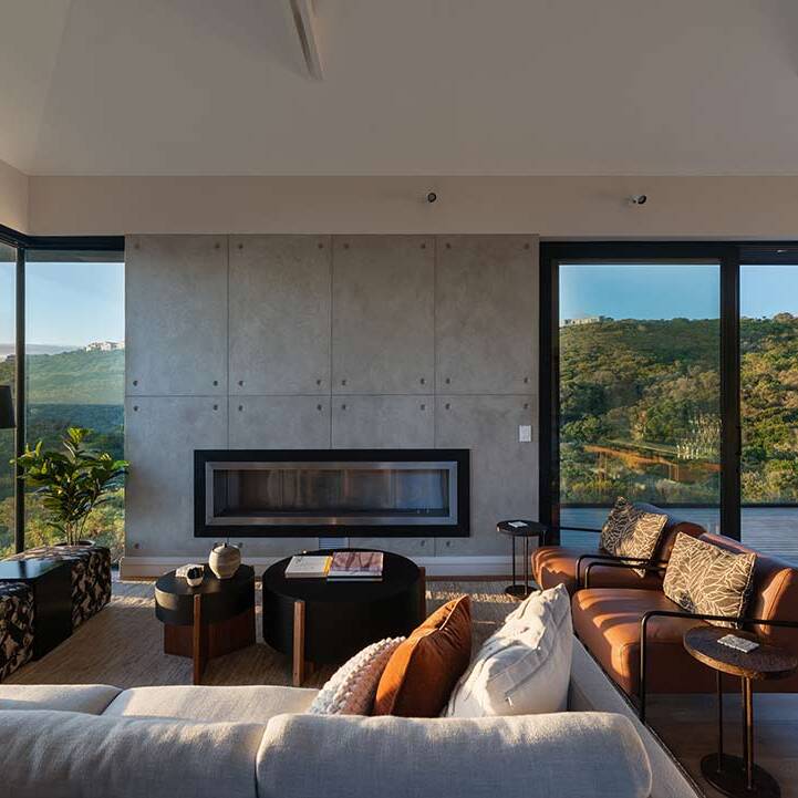 Living room with concrete fireplace wall and corner glazing to coastal fynbos, House 1418