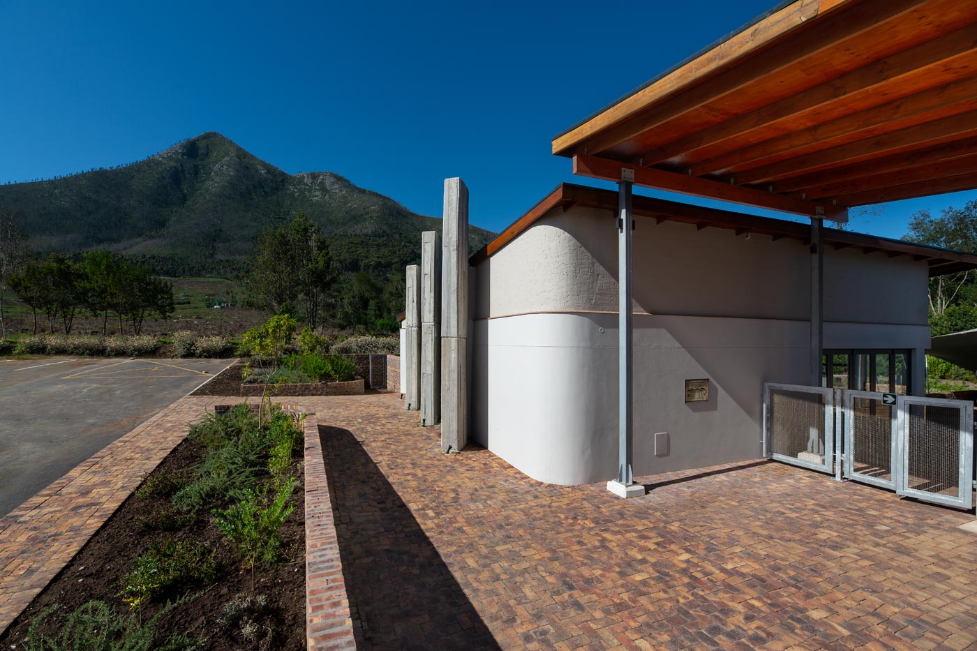 Curved rendered wall and timber roof with mountain backdrop at visitor centre